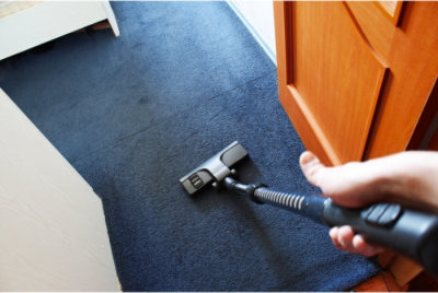 using a vacuum to clean the floor mat